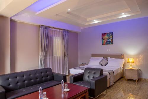 une chambre d'hôtel avec un lit et un canapé dans l'établissement Bukandula Hotel, à Kampala