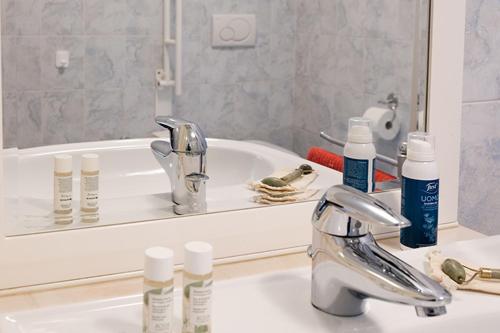 un lavandino in bagno con bottiglie di acqua ofodorizzatrici e specchio di Casa Angelo a Molveno