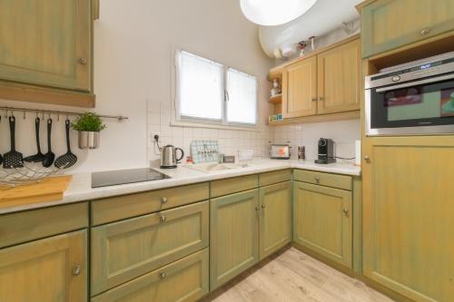 une cuisine avec des armoires vertes et un évier dans l'établissement LE PALAIS DU CHÊNE NOIR - HYPERCENTRE - CALME - WiFI GRATUIT, à Avignon