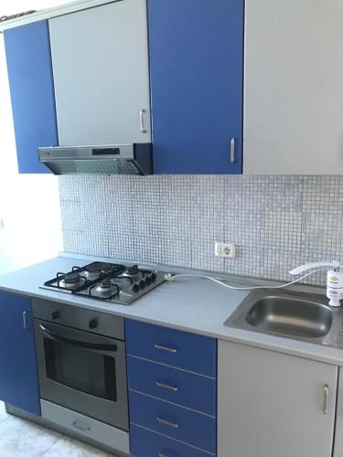 une cuisine avec une cuisinière, un évier et des placards bleus dans l'établissement orange room, à Durrës