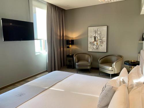a hotel room with a bed and two chairs at DS Hotel Lusopark in Santa Maria da Feira