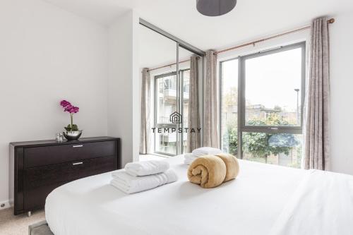 a white bedroom with a large bed with towels on it at Modern Private Apartment -Balcony-Tube Station in London