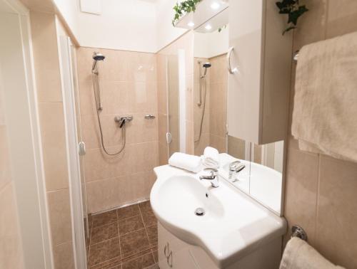 ein weißes Bad mit einem Waschbecken und einer Dusche in der Unterkunft Appartements Romanin in Pörtschach am Wörthersee