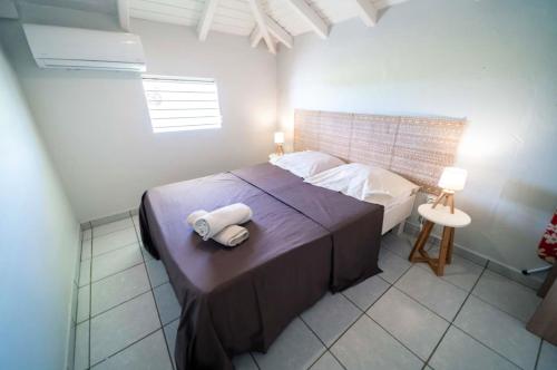 une chambre avec un lit avec deux serviettes dessus dans l'établissement Maison charmante à Sainte-Anne avec piscine partagée., à Sainte-Anne