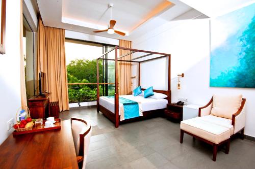 a bedroom with a bed and a table and a chair at The Lake Forest Hotel in Anuradhapura