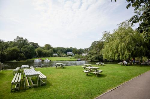 a park with picnic tables and a river at The Swan Hotel and Spa in Newby Bridge