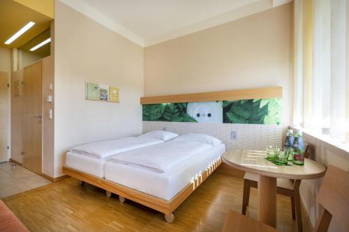 a bedroom with a bed and a table at JUFA Hotel Bleiburg - Pliberk in Bleiburg