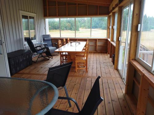 een afgeschermde veranda met een tafel en stoelen bij Charmy house with the nature just around the corner in Trollhättan