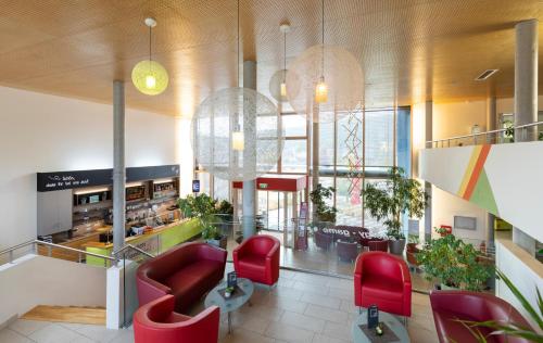 a lobby with red chairs and a restaurant at JUFA Hotel Bleiburg - Pliberk in Bleiburg