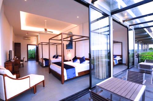 a bedroom with two beds and a balcony at The Lake Forest Hotel in Anuradhapura