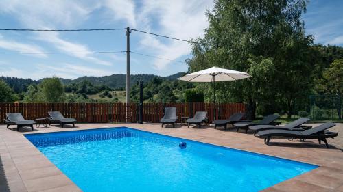 a swimming pool with chairs and an umbrella at Chalets Runolist in Crni Lug