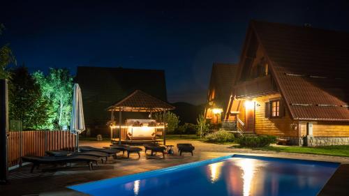 a swimming pool in front of a house at night at Chalets Runolist in Crni Lug