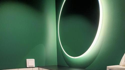 a bathroom with a green wall with a round mirror at Treetop Spa Hangout & Hotel in Gothenburg