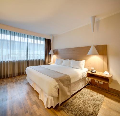 a bedroom with a large bed and a large window at Wyndham Concepcion Pettra in Concepción