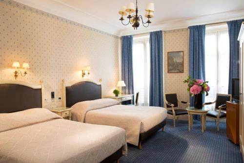 a hotel room with two beds and a desk at HOTEL DU PRINTEMPS in Paris