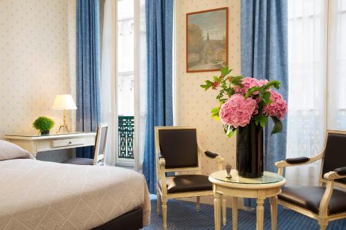a hotel room with a bed and a vase of pink flowers at HOTEL DU PRINTEMPS in Paris