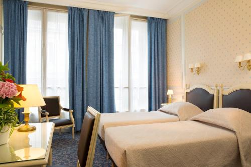 two beds in a hotel room with blue curtains at HOTEL DU PRINTEMPS in Paris
