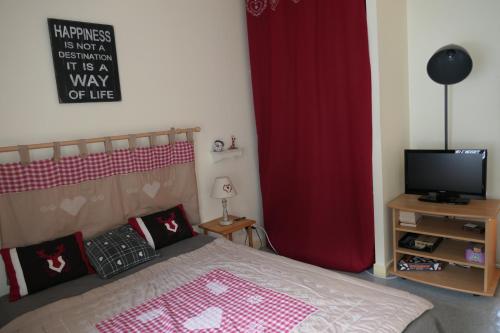 - une chambre avec un lit doté d'un rideau rouge et d'une télévision dans l'établissement Location Le Pim's à 