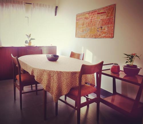mesa de comedor con sillas y mantel blanco en PARUL - Elegant Heritage Home at the Heart of Shantiniketan, en Santiniketan