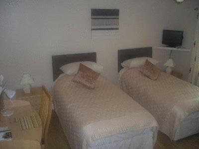 a bedroom with two beds and a table with a television at Meadowside B&B in Cupar