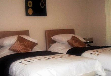 two beds in a hotel room with white sheets at Meadowside B&B in Cupar