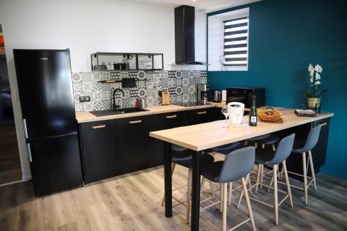 - une cuisine avec une table en bois et un réfrigérateur noir dans l'établissement Appart’Edith - Charmant appartement de tourisme, à La Neuville-aux-Larris