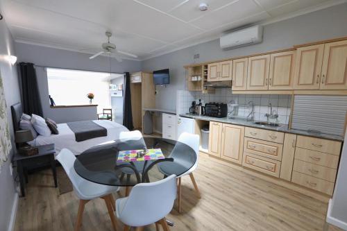 a kitchen with a table and white chairs in a room at Caesar's Self-catering Open Plan Suite in Somerset West