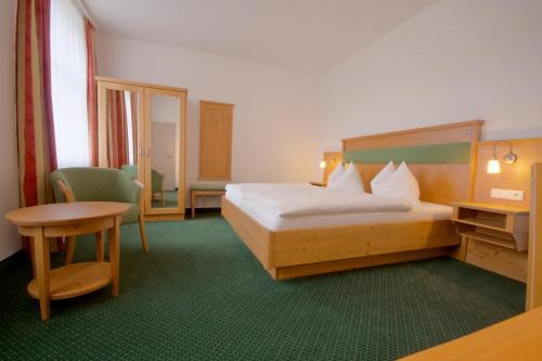 ゼープニッツにあるPension Am Finkenbergのベッドとテーブルが備わるホテルルームです。