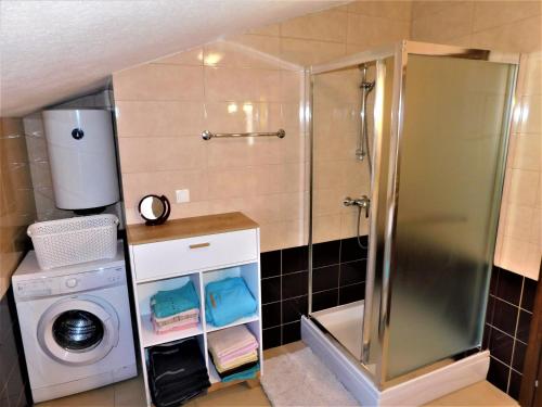 a bathroom with a shower and a washing machine at Apartman "Sabine" with pool in Omišalj