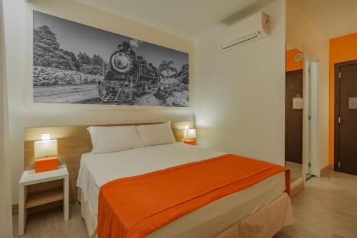 a bedroom with a large bed with a painting on the wall at Slim Bento Gonçalves in Bento Gonçalves