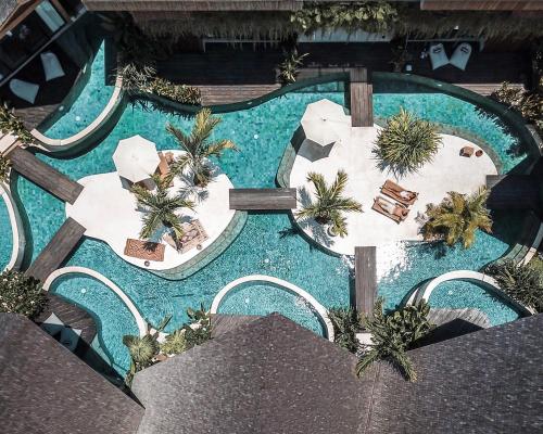 an overhead view of a pool with tables and palm trees at Beyond Bayou in Seminyak