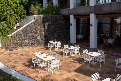 a patio with tables and chairs and a stone wall at Nazaret Mansion in Costa Teguise
