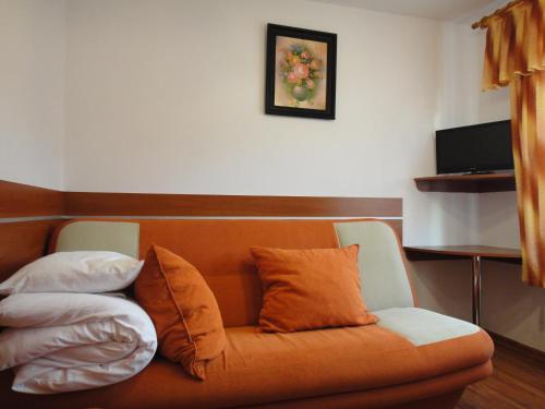 an orange couch with pillows on it in a room at Mirex in Krynica Zdrój