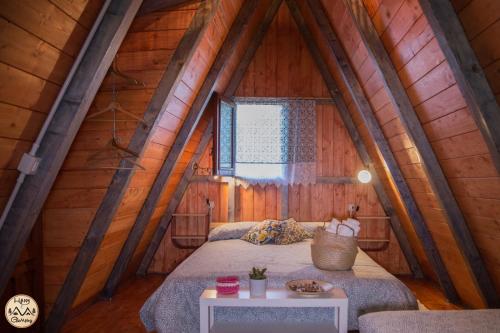 1 dormitorio en un ático de madera con cama y mesa en HAPPY GLAMPING MADONIE, en Polizzi Generosa