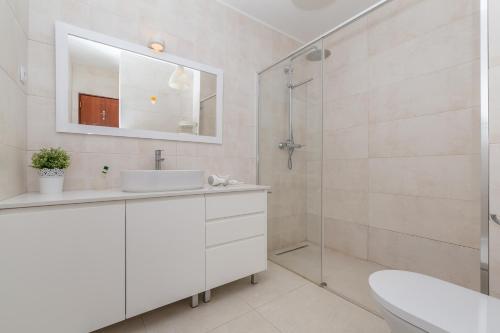 a white bathroom with a sink and a shower at Akisol Lagos Sand in Lagos