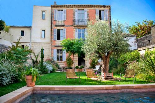 a house with chairs and a pool in front of it at La Maison Rouge d'Uzes B&B in Uzès