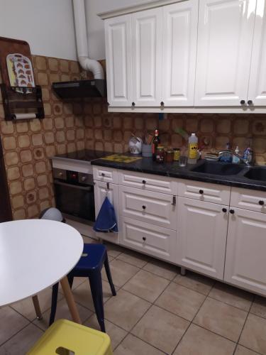 a kitchen with white cabinets and a sink and a table at Appartement atelier d'artiste in Vanves