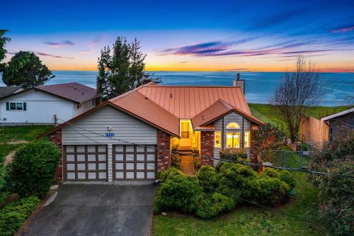 a house with a garage with a sunset in the background at @ Marbella Lane – Wave House, Your Oceanfront Retreat! in Oak Harbor