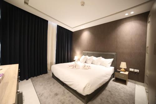 a bedroom with a large bed with white sheets and pillows at فندق صحارى الخليج Sahara Gulf Hotel Apartments in Amman