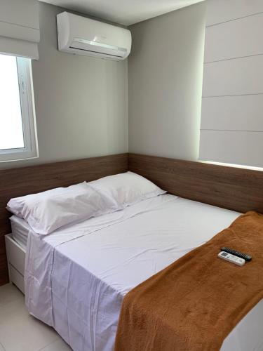 a bedroom with a bed with a remote control on it at Flatsportojjp - Flat Cupe Beach in Porto De Galinhas