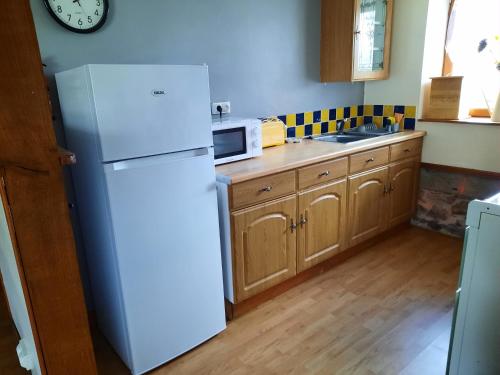 a kitchen with a white refrigerator and a microwave at La Pitardière Gite in Villaines-la-Juhel