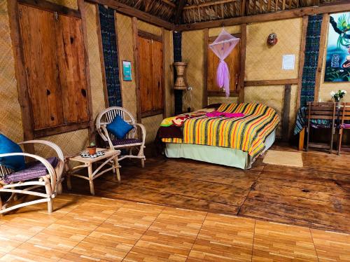 a bedroom with a bed and chairs in a room at Eco-Hotel Mayachik in San Juan La Laguna