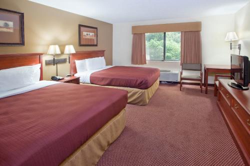 a hotel room with two beds and a flat screen tv at University Inn in Boiling Springs