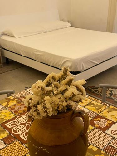 a vase with flowers on a table with a bed at Ad Maiora Salento in Lecce