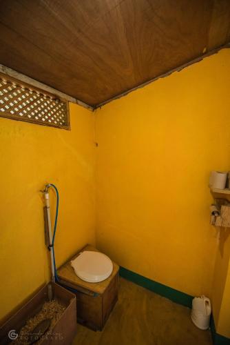 a bathroom with a toilet in a yellow wall at Eco-Hotel Mayachik in San Juan La Laguna