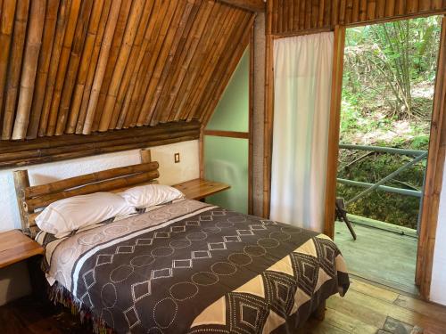 1 dormitorio con 1 cama en una habitación con ventana en Cabañas Aldea San Francisco de Asís en Cuetzalán del Progreso