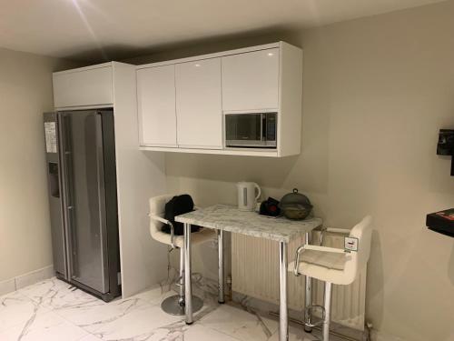 cocina con armarios blancos, mesa y sillas en Superb Double Bedroom en Londres