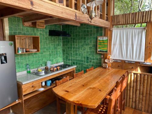 a kitchen with a wooden table and green tiles at Cabañas Aldea San Francisco de Asís in Cuetzalán del Progreso