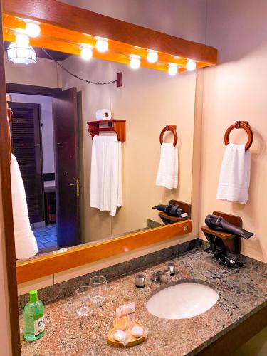 a bathroom with a sink and a large mirror at Pousada O Cantinho da Raposa in Monte Verde