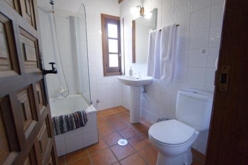 a white bathroom with a toilet and a sink at Casas Arbillas in Arenas de San Pedro